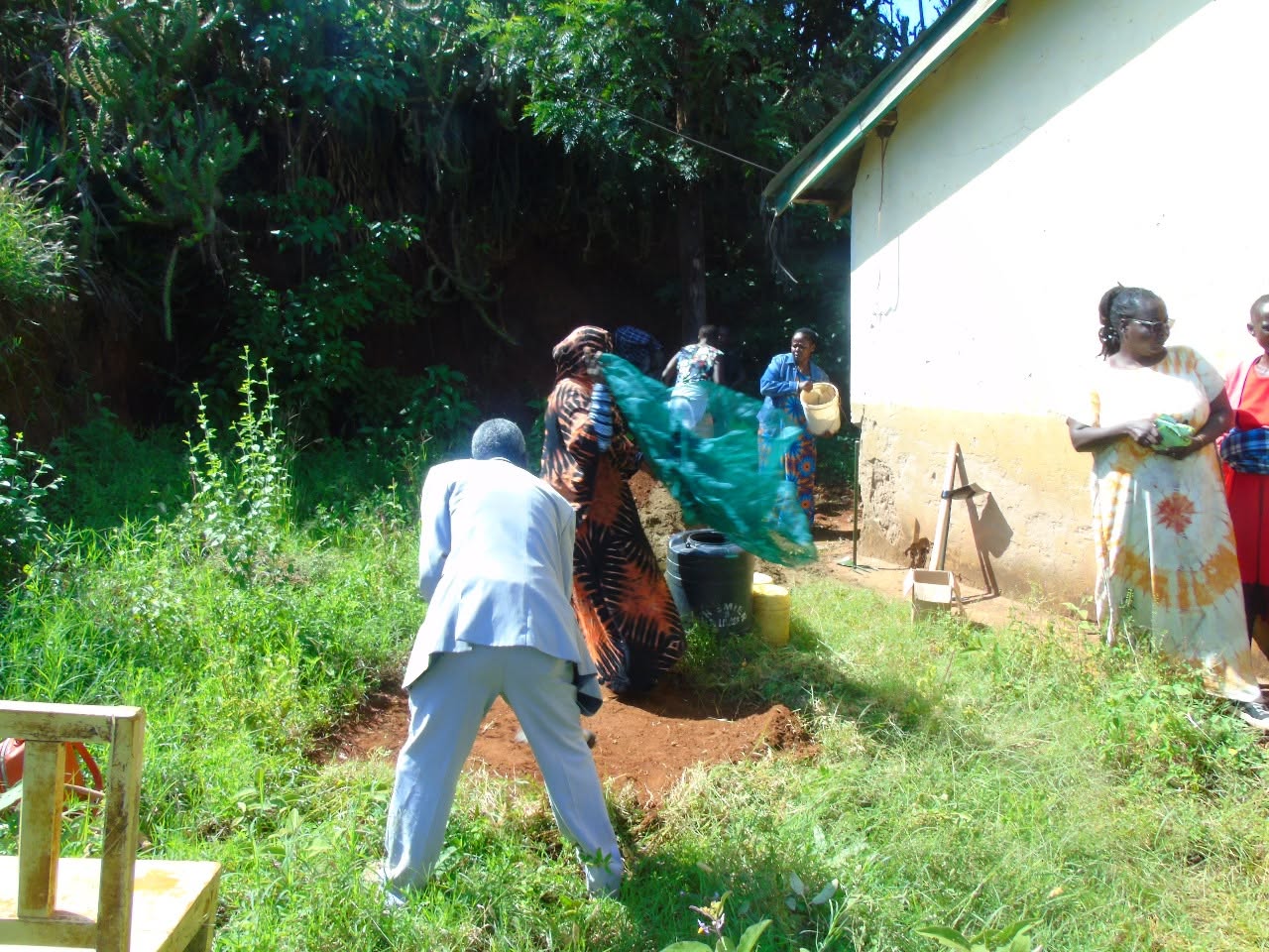 Participants digging and fitting netting for a sack garden beside a building